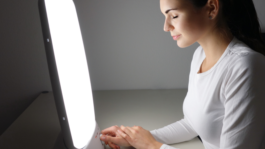 A woman using a light therapy box, a common treatment for Seasonal Affective Disorder (SAD).