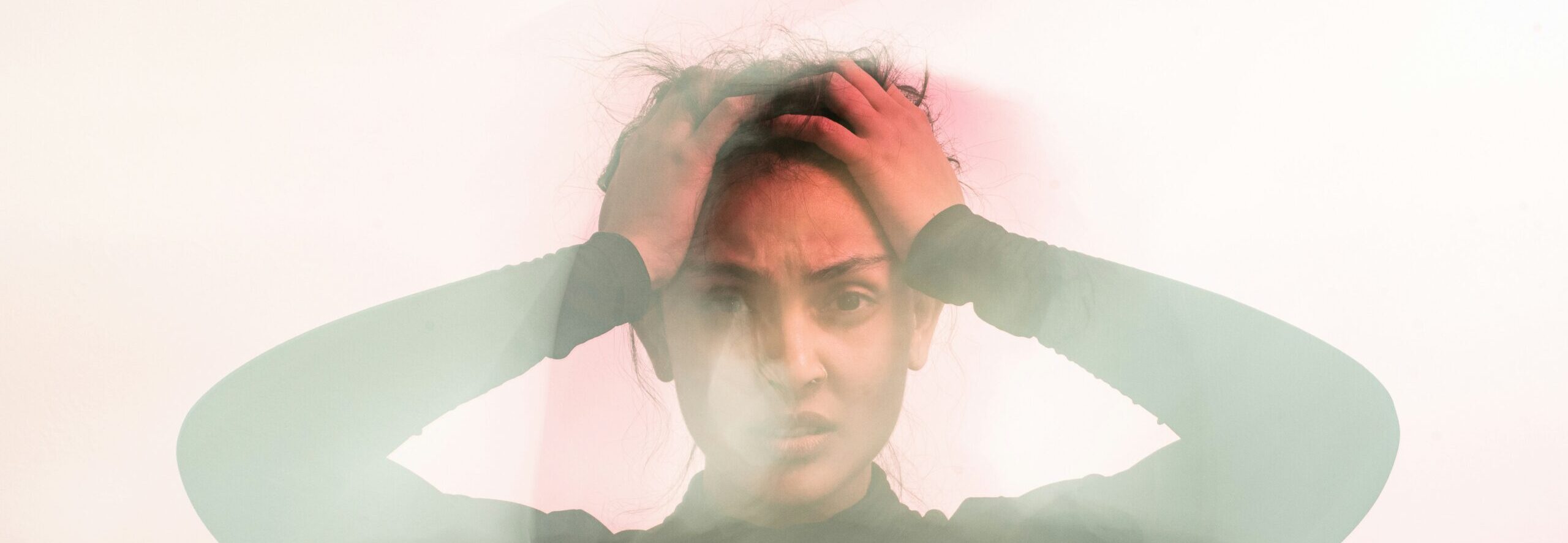 Woman holding head in blurry photo symbolizing the chaos of catastrophic thinking