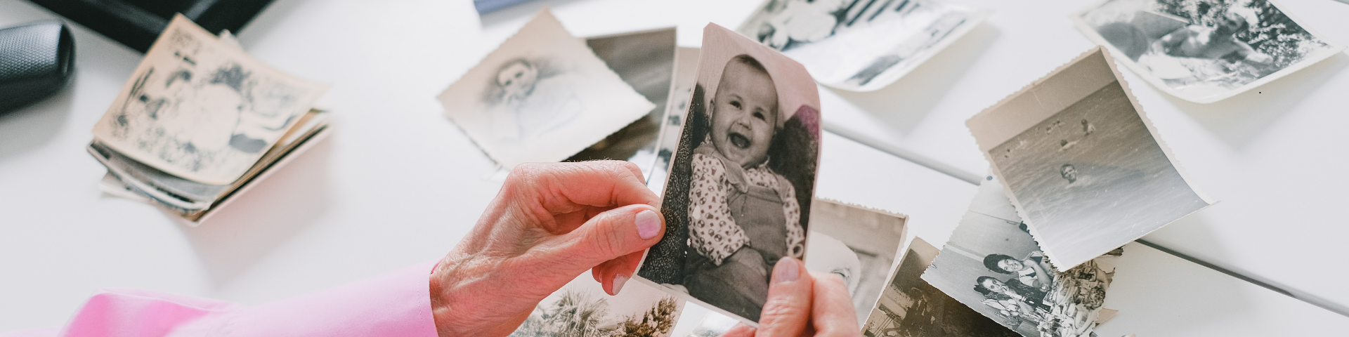 Older adult looking through family photos representing family history, genetics, and mental health risk across generations.